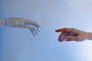 A robot hand reaches out to a human hand.