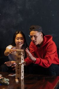 Two people playing a game where they stack wooden blocks into a tower.