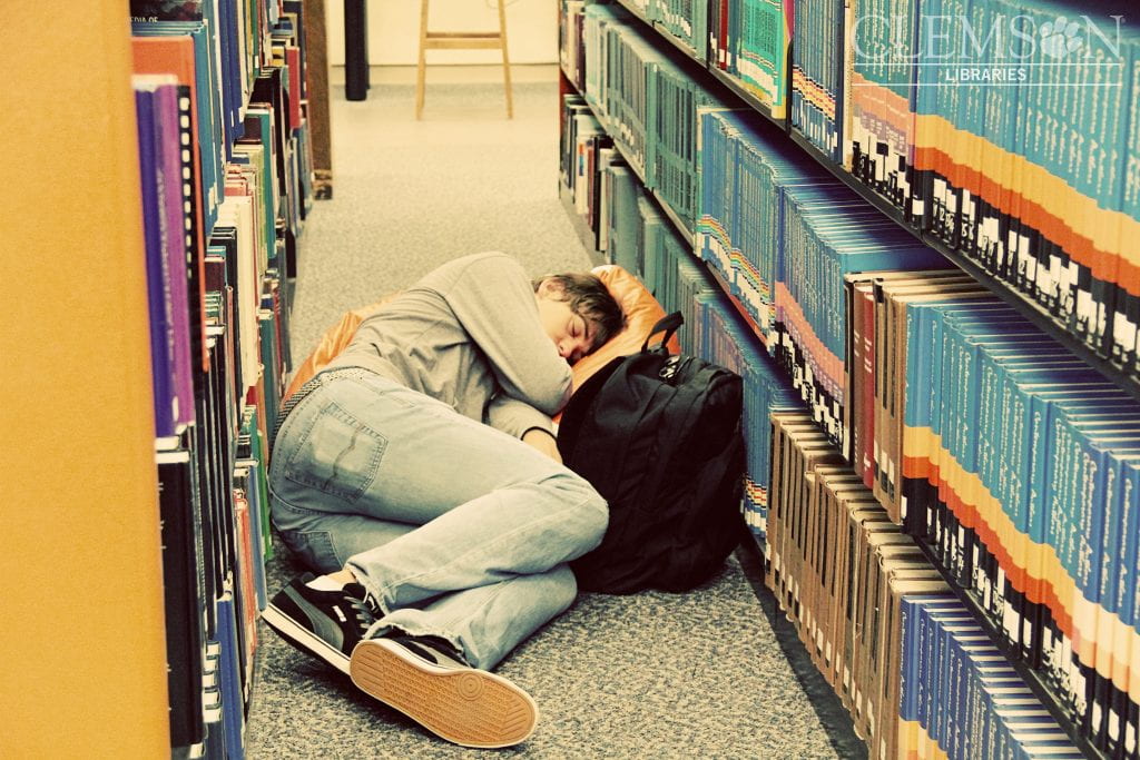Teenager asleep between library shelves