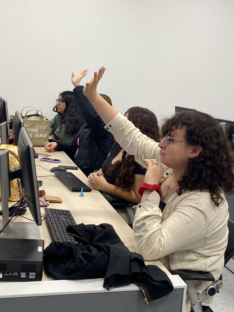 Students raising their hands to answer a question in class.